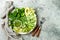 Vegan, detox Buddha bowl with avocado, zucchini noodles, green beans, spiralized cucumber, tomatoes, broccoli, lime and pesto