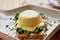 Vegan eggs benedict dish with wholegrain bread, creamy plant-based hollandaise sauce, smoked tofu, young onion, parsley