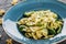 Vegan Farfalle pasta in a spinach sauce with broccoli, brussels sprouts, green beans in plate on dark stone background