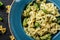 Vegan Farfalle pasta in a spinach sauce with broccoli, brussels sprouts, green beans in plate on dark stone background