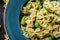 Vegan Farfalle pasta in a spinach sauce with broccoli, brussels sprouts, green beans in plate on dark stone background