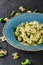 Vegan Farfalle pasta in a spinach sauce with broccoli, brussels sprouts, green beans in plate on dark stone background