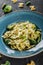 Vegan Farfalle pasta in a spinach sauce with broccoli, brussels sprouts, green beans in plate on dark stone background