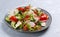 Vegan fattoush salad in a plate on a gray background.