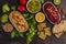 Vegan food background. Vegetarian snacks: hummus, beetroot hummus, green peas hummus, vegetables, cereals, tofu. Top view, dark b