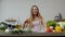 Vegan girl cooking salad with raw vegetables, adding lemon juice. Squeeze a lemon fruit in hands