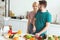 vegan girlfriend hugging boyfriend while he cutting vegetables