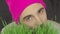 Vegan guy in a bright hat eats green grass