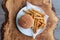 Vegan high protein soya burger in bun with salad, and chips on the side. Served on an olive wood platter.