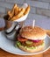 Vegan high protein soya burger in bun with salad, and chips on the side. Served on an olive wood platter.