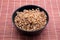 Vegan low calorie food, baked buckwheat in black round bowl studio shot on brown straw mat