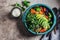 Vegan lunch bowl. Baked vegetables, quinoa and avocado salad in blue dish, dark background, top view