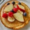 A vegan pancake served with various delicious and colorful fruits