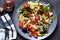 Vegan salad cabbage, spinach, tomatoes, peppers, avocados, onions with olive oil on the kitchen table. View from above