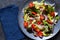 Vegan salad cabbage, spinach, tomatoes, peppers, avocados, onions with olive oil on the kitchen table. View from above