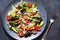 Vegan salad cabbage, spinach, tomatoes, peppers, avocados, onions with olive oil on the kitchen table. View from above