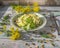 Vegan salad with fresh katusta with cucumbers with spicy herbs and seed seeds on a round lettuce plate, on the plank table a few