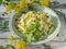 Vegan salad of fresh katusta with cucumbers with spicy herbs and seed seeds on a round lettuce plate, on a wooden turquoise table