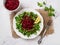 Vegan salad of lambs lettuce and raw beet. Fresh cornsalad leaves, grated raw beet and lemon slice on a white plate over marble