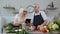 Vegan senior couple cooking salad with raw vegetables. Looking on digital tablet for online recipe