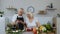 Vegan senior couple cooking salad with raw vegetables. Looking on digital tablet for online recipe