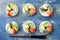 Vegan sushi donuts set with pickled ginger, avocado, cucumber, chives, nori and sesame on blue background. Sushi-food hybrid trend