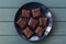 Vegan sweets. Tasty almond brownies on navy blue plate on turquoise background copyspace