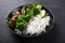 Vegan teryaki  tempeh or tempe buddha bowl  with rice, steamed broccoli, spinach  and lime on black  background. Healthy food