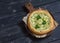 Vegan zucchini pizza on a rustic cutting board on dark wooden background.