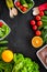 Vegearian lunch. Vegetables tomato, cucumber, asparagus, salad, orange on black background top view copyspace