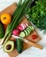 Vegen food on a light background, fresh vegetables and herbs on a cutting board top view