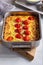 Vegetable clafoutis in baking dish on concrete background, savory pie with cabbage and whole cherry tomatoes .  Vegetarian cuisine