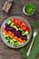 Vegetable cobs salad with stamates, cucumber, pepper, spinach and olive sauce on a wooden background. Salad is a rainbow