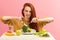 Vegetable diet. Sad dull woman holding broccoli on fork while making grimace