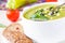 Vegetable green healthy cream soup with avocado, celery, zucchini and herbs in a white cup as a snack