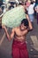 Vegetable market. Worker with heavy sack.