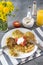 Vegetable pancakes, zucchini pancakes with sour cream and tomato on a plate, a bouquet of dandelions, a glass of orange juice,