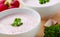 Vegetable radish soup. Bowl of cream radish soup surrounded by ingredients. Wooden background.