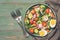 Vegetable salad with boiled egg served on a plate. Green rustic background, forks, napkin. Top view, copy space. Toned photo