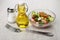 Vegetable salad, bottle of oil, salt and fork on table