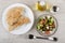 Vegetable salad, bottle of oil, salt, pita in plate