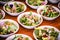 Vegetable salad, vegetables and flowers. multiple salad bowls with arugula, flower petals, vegan toast