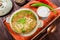 Vegetable soup, broth with noodles, herbs, parsley and vegetables in bowl with sour cream, spice, pepper, dried thyme and bread