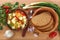 Vegetable soup of cauliflower, carrots, tomato, pepper in a plate with a spoon, bread and onions on a wooden background.