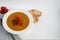 Vegetable soup with lentils on a white background. Served with chopped cherry tomatoes and herbs. Nearby are pieces of ciabatta.