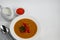 Vegetable soup with lentils on a white background. Served with chopped cherry tomatoes and herbs. Nearby are pieces of ciabatta.