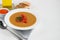 Vegetable soup with lentils on a white background. Served with chopped cherry tomatoes and herbs. Nearby are pieces of ciabatta.