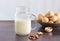 Vegetable walnut milk in a glass cup with a handle. Walnuts in a plate in the background. Healthy drinks, vegetarianism. Side view