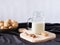 Vegetable walnut milk in a glass cup with a handle on a wooden cutting board. Walnuts in a plate in the background. Healthy drinks