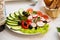 Vegetables beautifully sliced on a white dish. Cucumber, red tomato, red bell pepper, olives, radish, parsley leaf beautifully ser